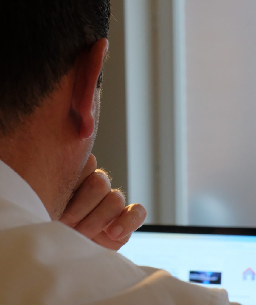 Das Foto zeigt den Blick über die Schulter von Philip Bunjes, Gründer und Inhaber von Shopmanagement Services, wie er am Laptop sitzt.